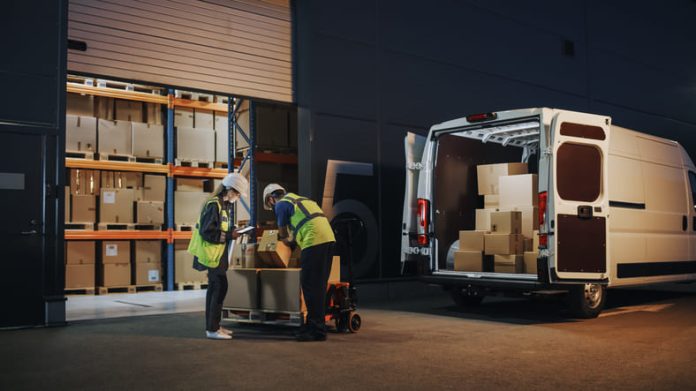Outside of Logistics Retailer Warehouse With Female Manager Using Tablet Computer, Worker Loading Delivery Truck with Cardboard Boxes and materials