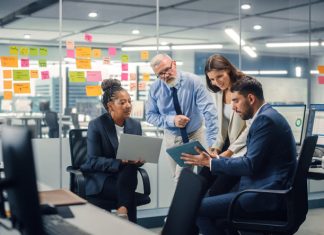 In Modern Office: Diverse Team of Managers Use Laptop and Tablet Computers at a Company Meeting Discussing Link Campaigns and Business Projects.