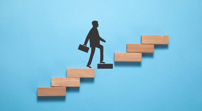 Businessman climbing on career ladder made by wooden block.