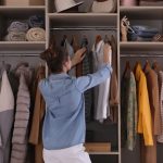 Young woman choosing clothes in wardrobe closet