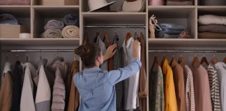 Young woman choosing clothes in wardrobe closet