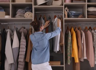 Young woman choosing clothes in wardrobe closet