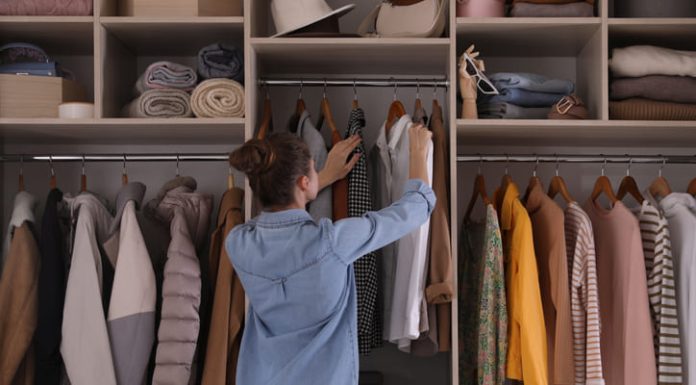 Young woman choosing clothes in wardrobe closet