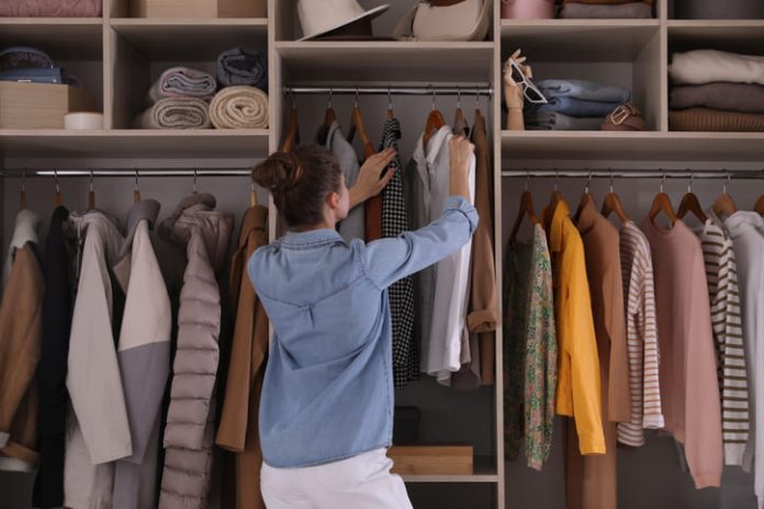Young woman choosing clothes in wardrobe closet
