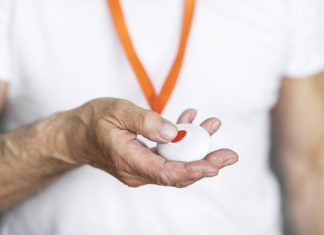 Elderly man pressing alarm button for emergency hung on his chest