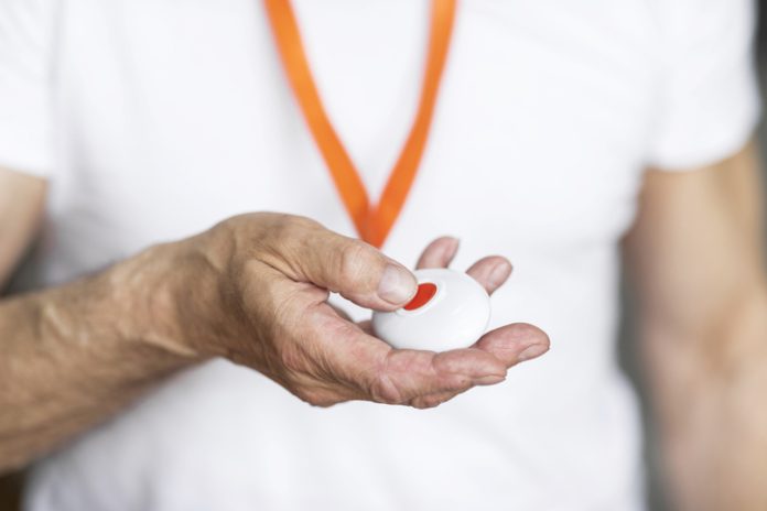 Elderly man pressing alarm button for emergency hung on his chest