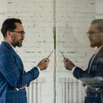 Businessman holding a pen looking at himself in the mirror