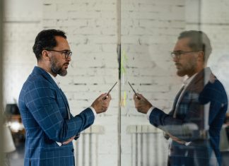 Businessman holding a pen looking at himself in the mirror