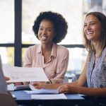 Why Nick Muzin Uses a Month-to-Month Model for Services Business Team Meet Around Boardroom Table With Laptops Discussing services and documents