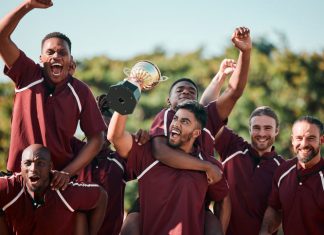 Cricket players celebrating, cheering and holding trophy at competition.