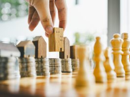 Chess, stack of coins and house models in chess game, competition success play. strategy, management or leadership