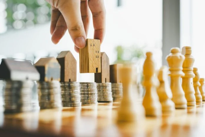 Chess, stack of coins and house models in chess game, competition success play. strategy, management or leadership