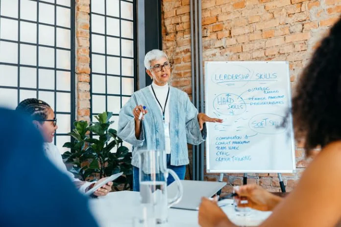 iStock-2183701424 (1) leader of the leaders presenting a strategy on leadership skills to engaged, diverse colleagues in a fresh and innovative office setting.