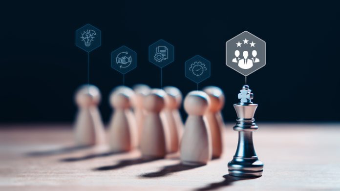 Chess king stands with wooden figures and leadership icons, representing the concept of effective leadership, meritocracy, highlights the importance of strategy, competition and intelligence in achieving success