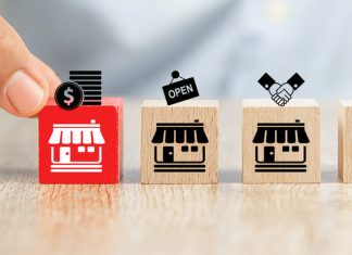 Close-up hand choose cube wooden toy blocks place in line up with franchise business store icon. Clause in Franchising