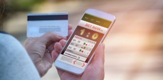 Man betting on sports, holding smart phone with working online betting mobile application