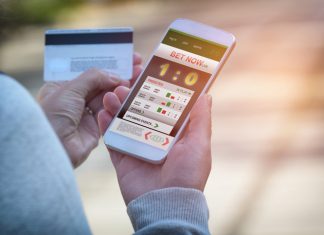 Man betting on sports, holding smart phone with working online betting mobile application