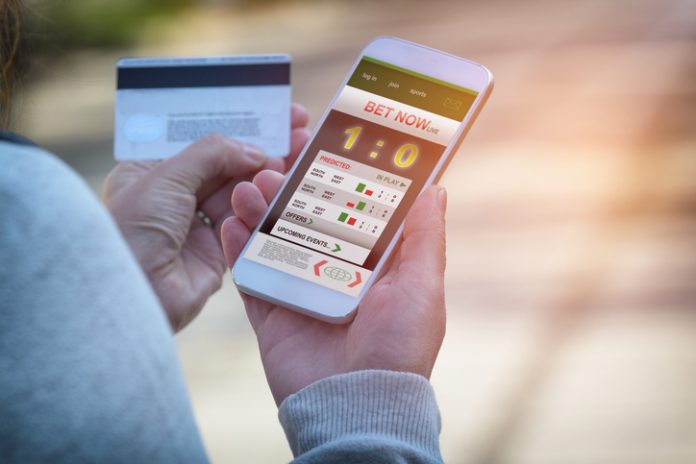 Man betting on sports with smartphone Man betting on sports, holding smart phone with working online betting mobile application