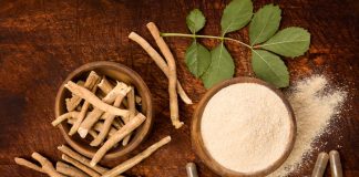 Ashwagandha superfood powder and root on cutting board on wooden table from above.
