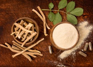 Ashwagandha superfood powder and root on cutting board on wooden table from above.