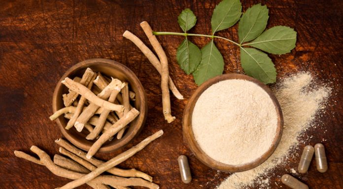 Ashwagandha superfood powder and root on cutting board on wooden table from above.