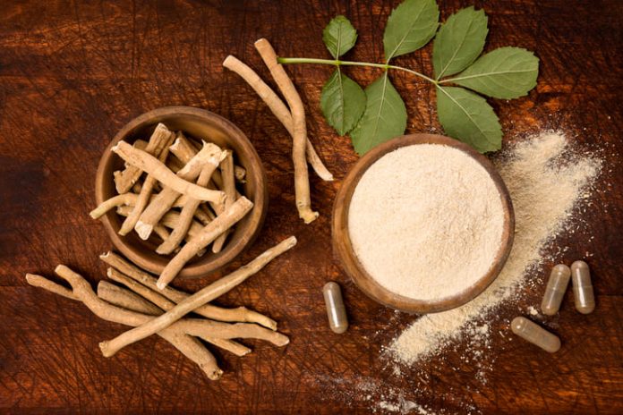 Ashwagandha superfood powder and root on cutting board on wooden table from above.