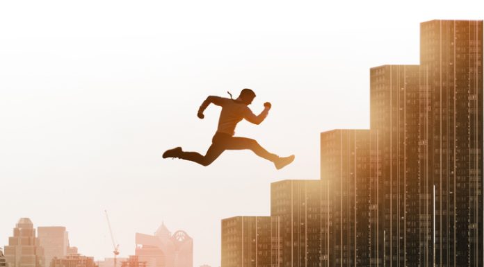 Young businessman jumping high and leap on staircase, celebrate success winning pose on building rooftop.