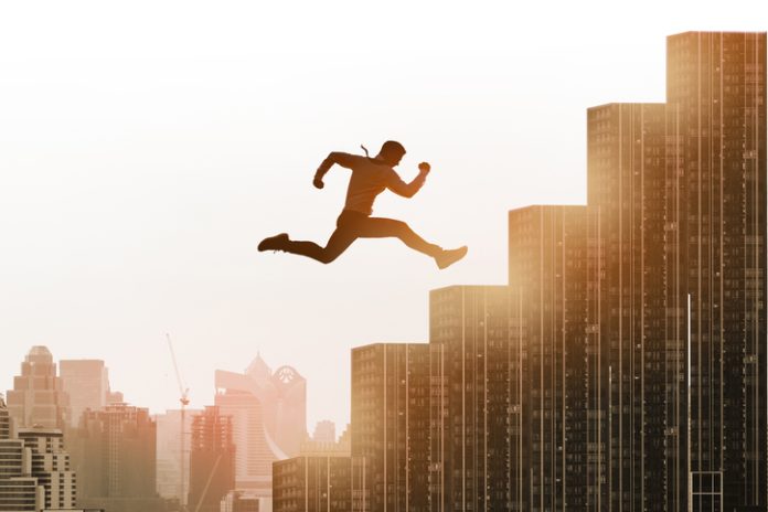 Young businessman jumping high and leap on staircase, celebrate success winning pose on building rooftop.