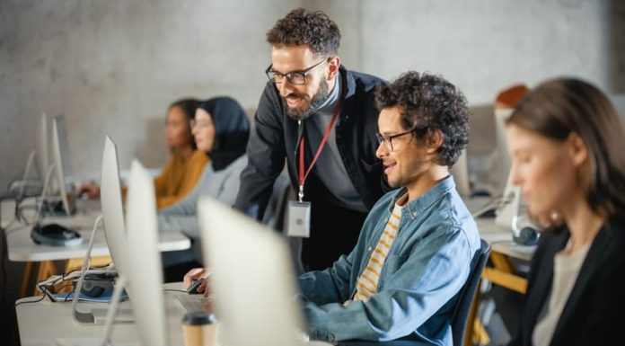 Teacher Giving Lesson to Diverse Multiethnic Group of Female and Male Students in College Room, Teaching New Academic Skills on a Computer in Germany