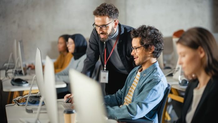 Teacher Giving Lesson to Diverse Multiethnic Group of Female and Male Students in College Room, Teaching New Academic Skills on a Computer in Germany