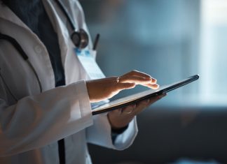 Benefits of Care Coordination Software Telehealth, digital tablet and doctor hands for hospital innovation, software management and results update in dark workplace. Healthcare, cardiology and telecom medical professional with technology