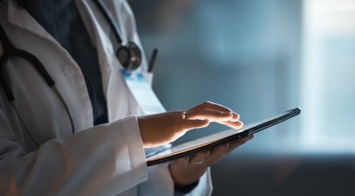 Telehealth, digital tablet and doctor hands for hospital innovation, software management and results update in dark workplace. Healthcare, cardiology and telecom medical professional with technology