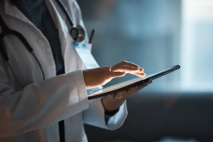 Telehealth, digital tablet and doctor hands for hospital innovation, software management and results update in dark workplace. Healthcare, cardiology and telecom medical professional with technology