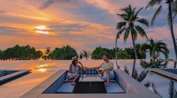 The Smart Money is Staying In Couple watching sunset in infinity pool on a luxury space during vacation