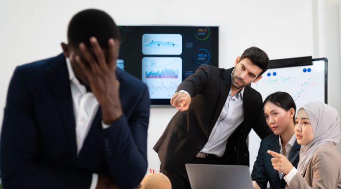 group of business people pointing and talking rumor spread behind stress colleague at workplace, diverse coporate employee gossip and bully black person while meeting in financial office.