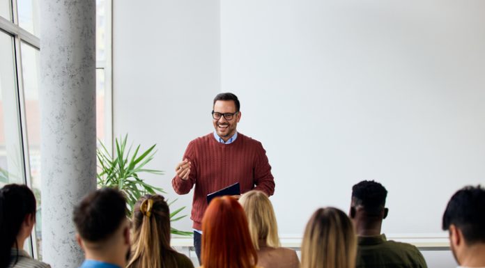 Corporate speaker delivering a motivating training about affirmation to a group of diverse employees.