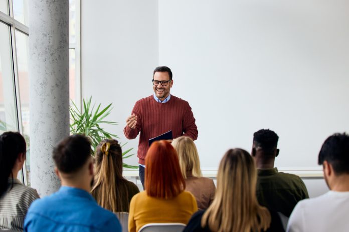 Corporate speaker delivering a motivating training about affirmation to a group of diverse employees.