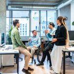 Business team discussing ideas, reputation equity in modern office with disabled colleague
