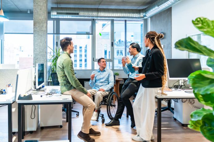 Business team discussing ideas, reputation equity in modern office with disabled colleague