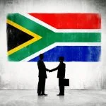 Investing in Africa this Year: The 5 Best Businesses to Start Two Businessmen Shaking Hands With Flag Of South Africa As A Background