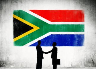 Two Businessmen Shaking Hands With Flag Of South Africa As A Background