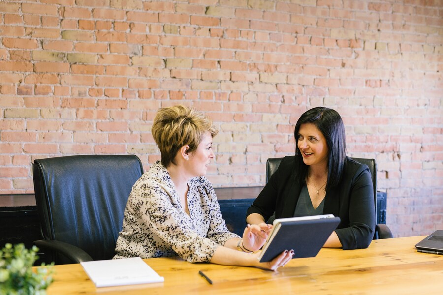two women sitting on leather chairs in front of table discussing about the salary