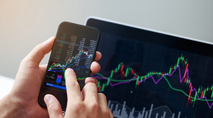 Businessman hand holding phone and analysis finance market graph stock market trading, stock chart and investment