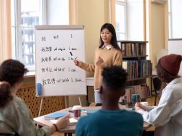 Portrait of young Asian woman teaching Chinese language to a group of employees