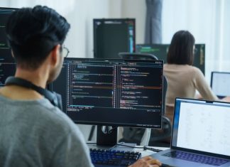 AI is Making Us Stupider, And That’s Exactly Why We Need to Talk software developers working on multiple screens displaying code and application diagrams in a modern office