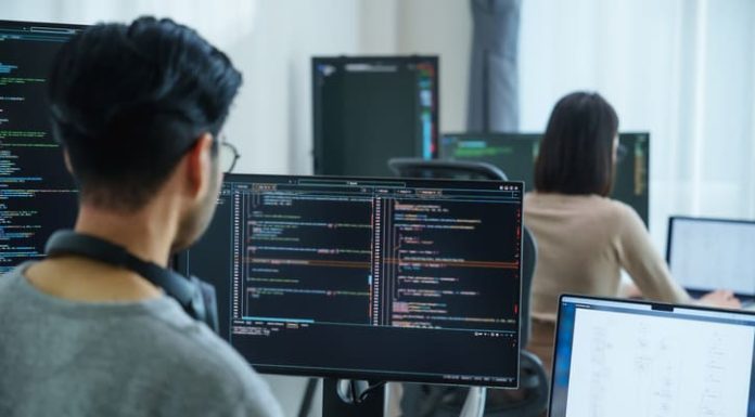 software developers working on multiple screens displaying code and application diagrams in a modern office