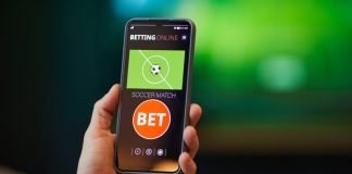 How to Start Betting on Sports: Step by Step Sports Betting Guide Close-up of hand holding smartphone with soccer betting app interface showing bet options and match information in background