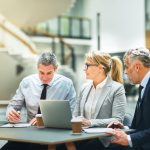 Empowering Communities: The Economic Impact of Social Entrepreneurship in Europe Mature businesspeople sitting at a table talking and using a laptop while having a meeting together about entrepreneurship