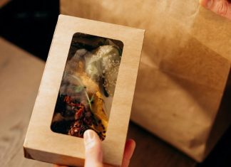 Food in a Carboard Box and a Paper Bag on a Wooden Surface