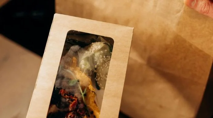 Food in a Carboard Box and a Paper Bag on a Wooden Surface